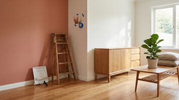 Kategorie Farben - Helles Wohnzimmer mit frisch gestrichener Wand. Farbrolle und Holzleiter stehen auf dem Holzboden und lehnen an der Wand an. Wandfarben und Holzfarben zur Gestaltung von Innenräumen und Holzmöbeln.